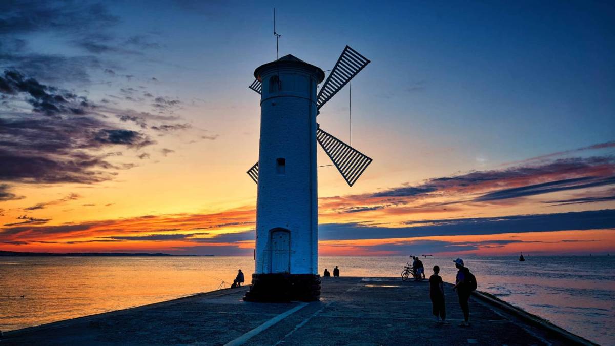 Kuvassa tuulimyllyn muotoinen majakka Swinemündessa. Taustalla auringonlasku. 
