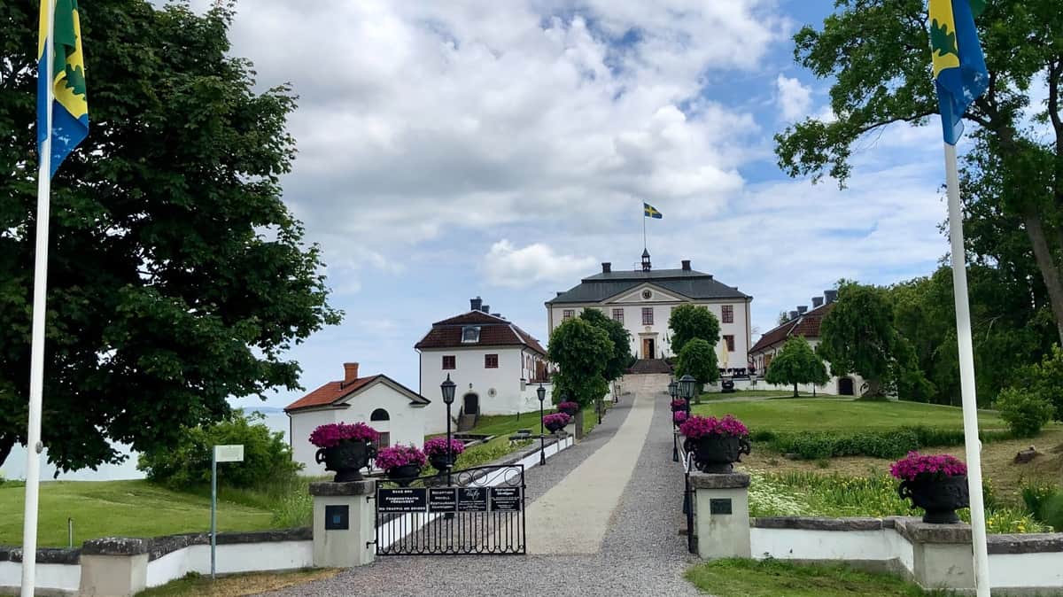 Ruotsissa sijaitseva vaalea linnamainen rakennus, jonka ympärillä siisti nurmialue ja kasveja.