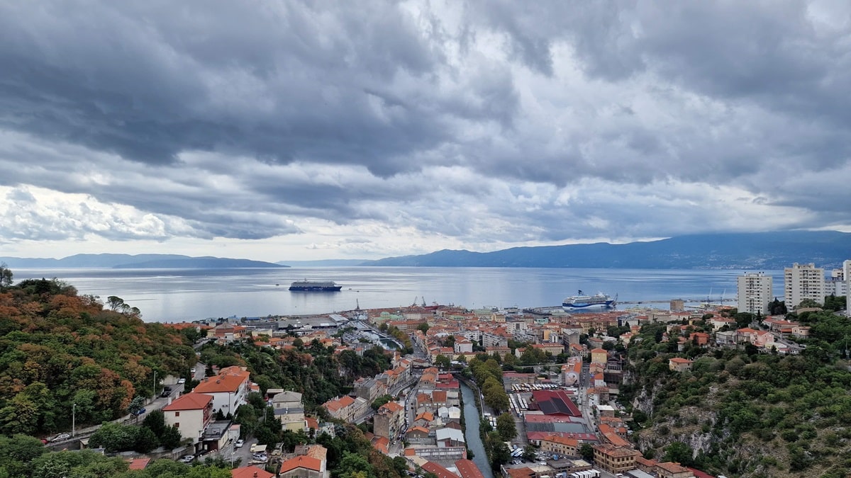 Rijekan kaupunki Kroatiassa, etualalla punatiilikattoisia taloja kuvattuna ylhäältä päin. Taustalla meri ja pilvinen taivas.