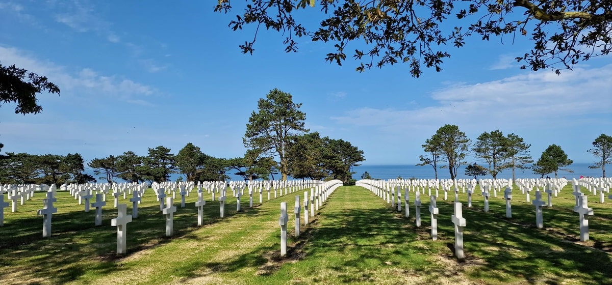Normandian maihinnousurannikolla sijaitseva amerikkalaisten hautausmaa, valkoisia ristejä rivissä nurmikolla.