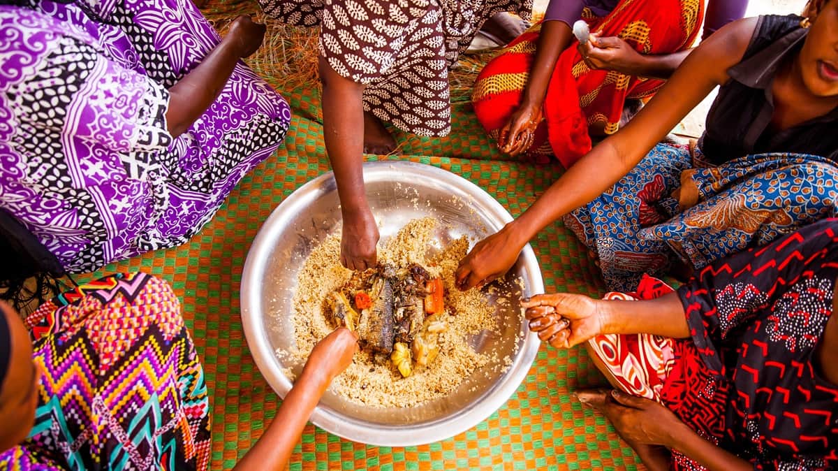Senegalilaisia naisia syomassa ruoka ja juoma