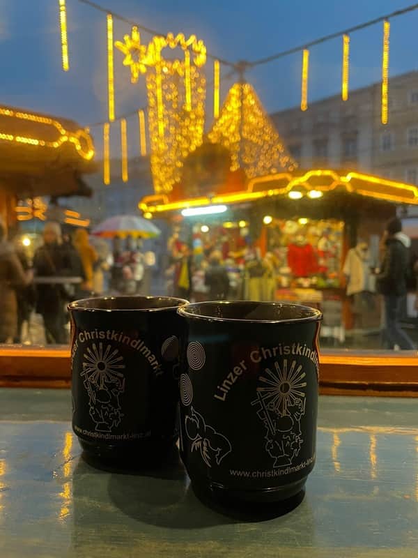Euroopan joulumarkkinat Elina Ryhanen Kaksi glühwein-mukia pöydällä. Taustalla eurooppalaisten joulutorien tunnelmaa.