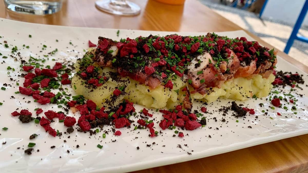 Ruokamatkan annos Ruokamatkailun helmi, mustekalaa, perunaa ja oliivi-kirsikkapölyä