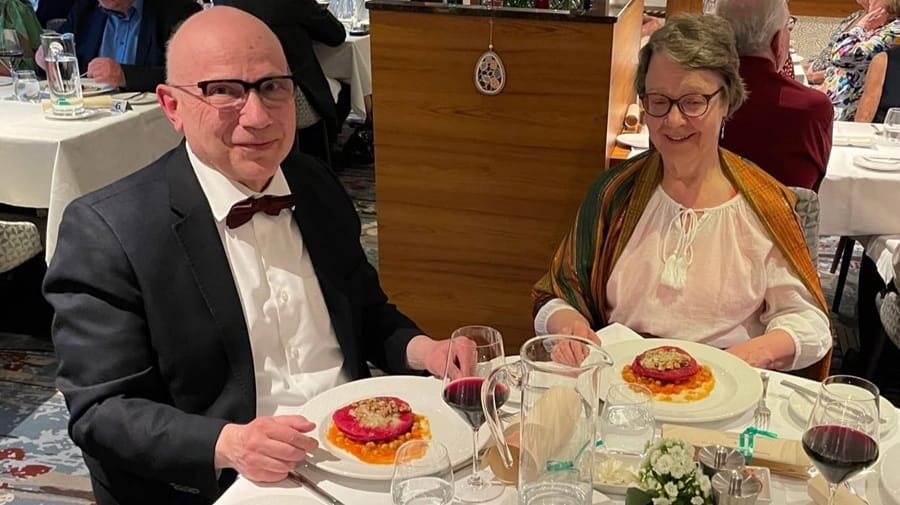 Nainen ja mies juhla-asuissaan illallispöydässä.