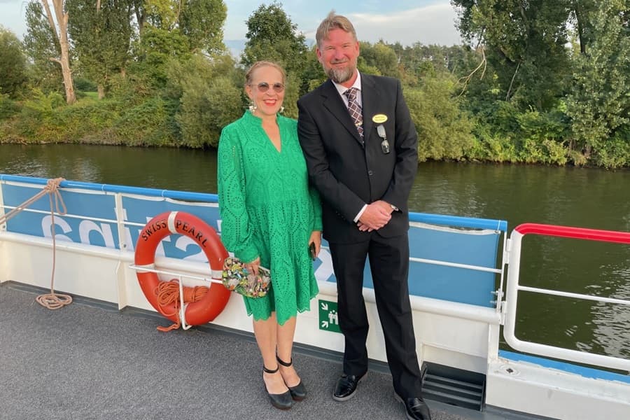 Kaksi matkanjohtajaa seisoo juhlavaatteita jokilaivan kannella.