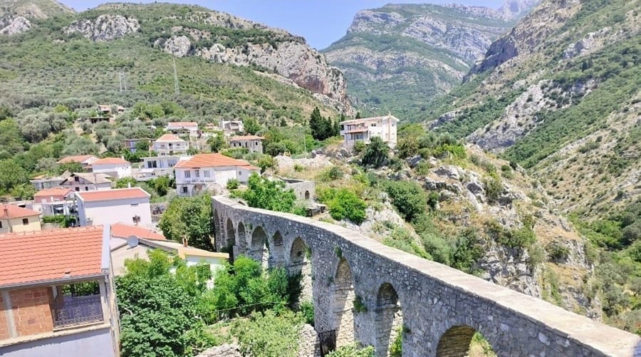Vanha kivisilta Montenegrossa, jonka ympärillä vehreää puustoa ja vuoristoa.