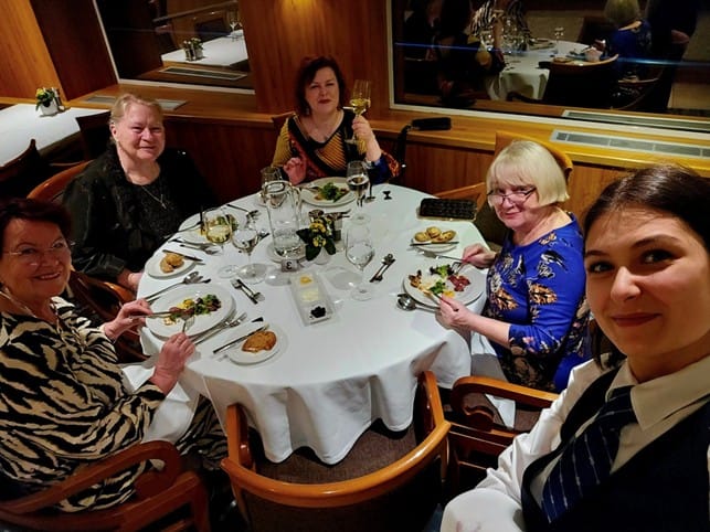 Neljä henkilöä pyöreän illallispöydän äärellä jokiristeilyllä.