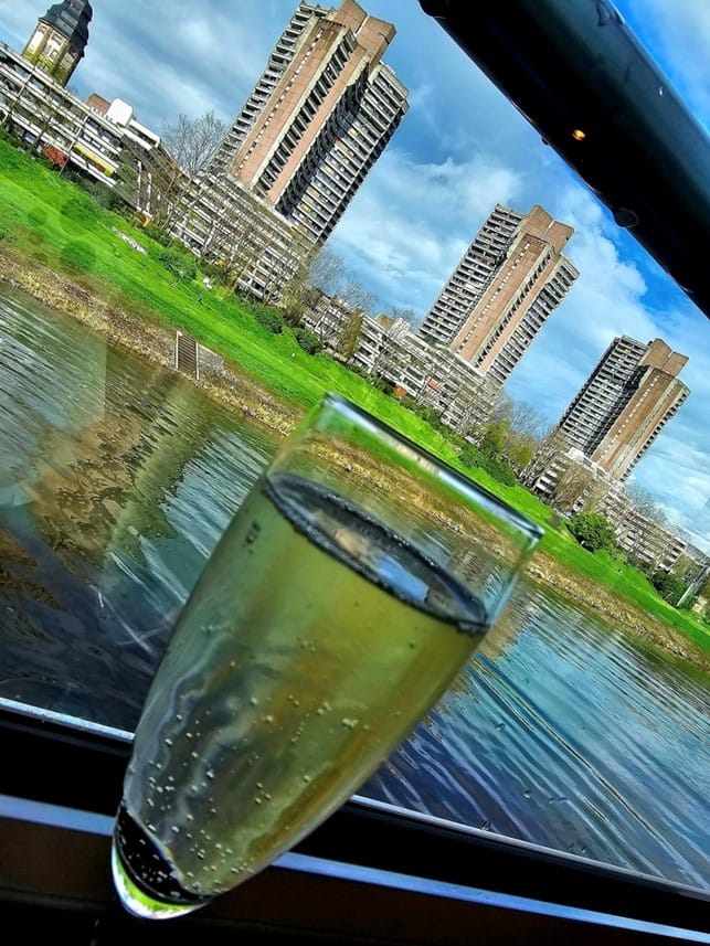 Kuohuoviinilasi, jonka taustalla joki ja kaupunkimaisema. 