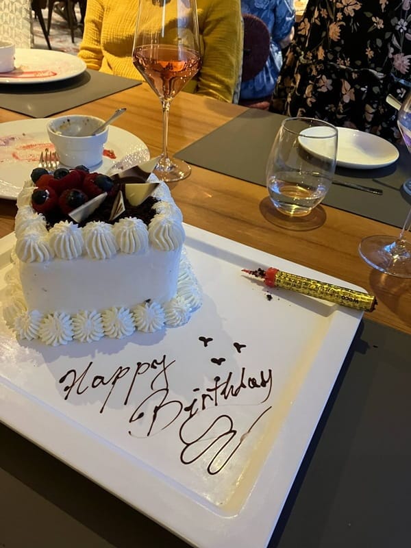 Syntymäpäiväkakku, jonka lautaselle on kirjoitettu suklaalla ”happy birthday”.